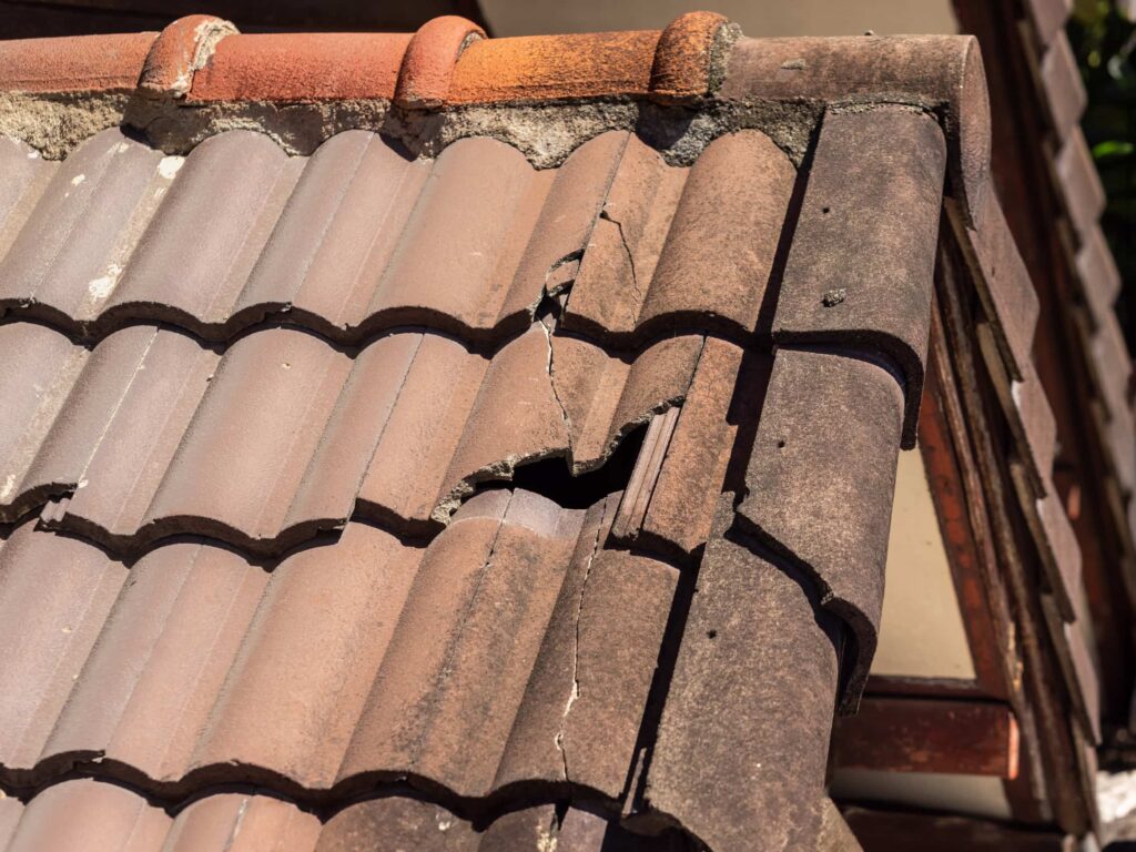 Cracked and broken concrete tile requiring urgent roof repairs